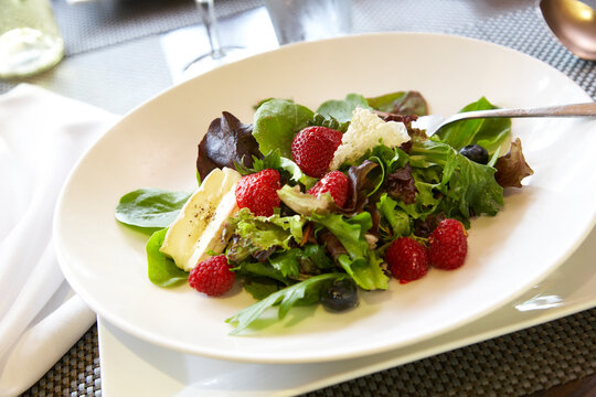 Fresh, organic salad greens with strawberries, blueberries, cheese and other healthy items.