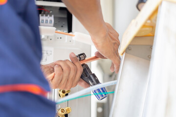 Young repairman team fixing air conditioner unit, Asian technician man installing an air conditioning in a client house, Maintenance and repairing concepts