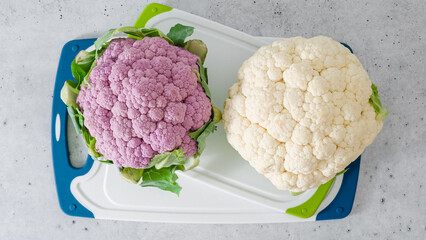 Cauliflower, white and purple, close-up on a cutting board, light gray stone background, flat lay