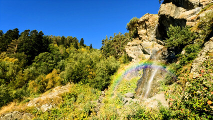 Fototapeta na wymiar mountain forest waterfall with rainbow at summertime, tourer experience - photo of nature