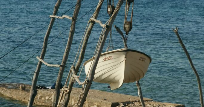 Boats hanging from traditional wooden cranes in Savudrija, Croatia