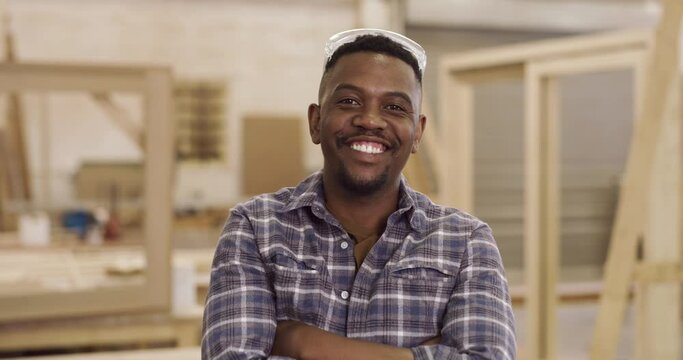 Portrait, happy and a black man carpenter arms crossed, standing in his workshop for creative manufacturing. Smile, construction and carpentry with a male designer working in his design factory