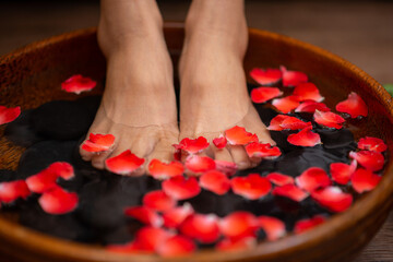 Woman soaks her feet in a bowl with flower petals