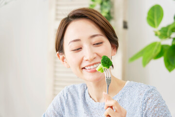 自宅でブロッコリーを食べる女性