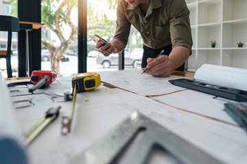 engineer checks construction blueprints on new project with engineering tools at desk in office