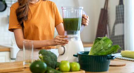 Portrait of beauty healthy asian woman making green vegetables detox cleanse and green fruit smoothie with blender.young girl drinking glass of green fruit smoothie in kitchen.Diet concept.healthy 