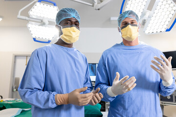 Portrait of diverse male surgeons with face masks in operating room