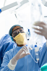 African american female surgeon with face mask preparing drip in operating room