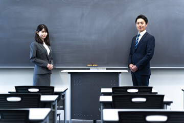 学校の黒板の前に立つ2人の先生