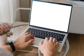 hand using laptop and typing on keyboard with mockup of blank screen.