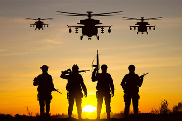 Silhouettes of soldiers with helicopters against the sunset. Military background
