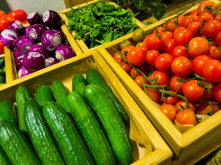 beautiful washed cucumbers and tomatoes lie neatly in a wooden box next to boxes with other vegetables. shop, restaurant, market, home