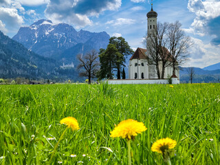 Meadow and beautiful old church in Bavaria with Neuschwanstein Castle and Bavarian Alps in distance...