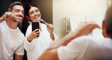 Selfie, brushing teeth and couple in a bathroom, mirror and happiness with hygiene, home and wellness. Partners, man or woman with a smile, social media or mouth cleaning with reflection or self care