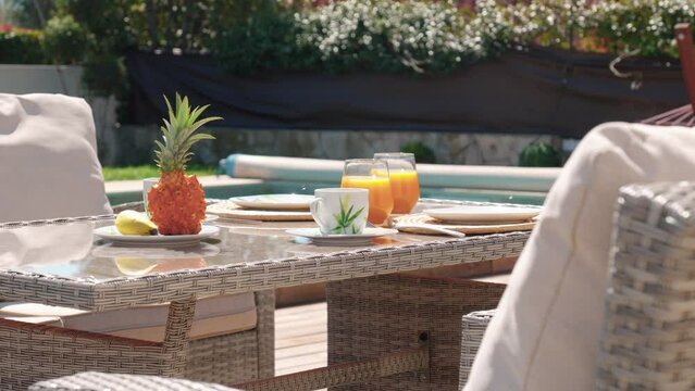 Fruits and orange juice set on a poolside table during a sunny day