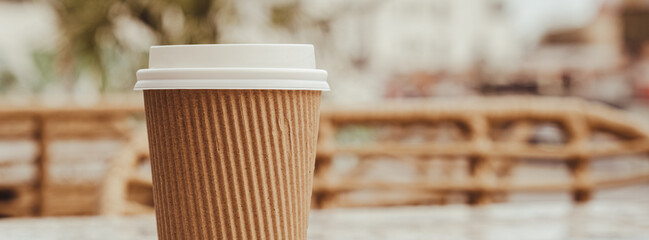 Eco recycling paper cup with coffee or tea on craft paper on table in beach cafe. Take away coffee to go. Copy space for text. Disposable Cardboard coffee outdoors
