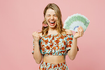 Young blonde woman wears summer casual clothes hold in hand fan of cash money in dollar banknotes...