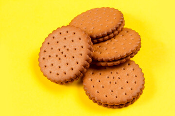 A pile of round cookies stuffed on a yellow background. Sweet biscuits filled with cocoa.