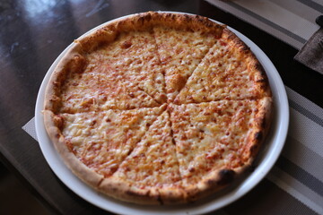 Beautiful pizza on a table. Tasty pizza in a frying pan. Delicious pizza on a wooden board.