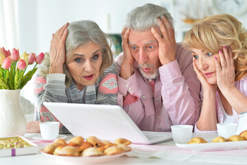 senior people with laptop drinking tea