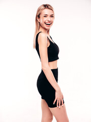 Fototapeta premium Young beautiful smiling blond female in summer black cycling shorts costume clothes. Sexy carefree woman posing on white in studio. Positive model having fun. Cheerful and happy