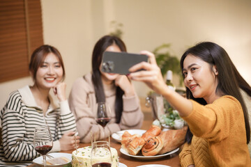 Asian sister friends making selfie and smiling with smartphone. celebrating with Birthday cake.