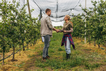 A man and a woman shake hand in the fruit farm.