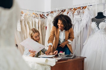 Designer shows the owner of a bridal salon designs for the new wedding dress collection.
