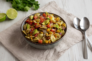 Homemade Grilled Corn Summer Pasta Salad in a Bowl on a white wooden background, low angle view.
