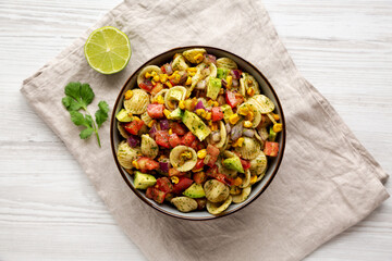 Homemade Grilled Corn Summer Pasta Salad in a Bowl on a white wooden background, top view. Flat lay, overhead, from above.