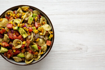 Homemade Grilled Corn Summer Pasta Salad in a Bowl on a white wooden background, top view. Flat lay, overhead, from above. Space for text.