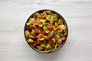 Homemade Grilled Corn Summer Pasta Salad in a Bowl on a white wooden background, top view. Flat lay, overhead, from above.