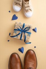 Sweet son surprises Dad on Father's Day. Overhead vertical shot of father's loafers, kid's sneakers, hearts, and gift box with blue ribbon bow on beige backdrop