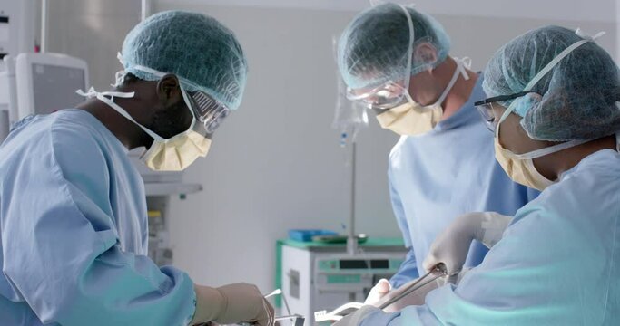 Focused diverse male and female surgeons with face masks during surgery in slow motion, unaltered
