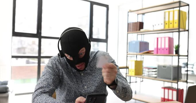 Man with mask and headset talks by videocall with potential victim of online theft. Fraud convinces to invest money in fictive project