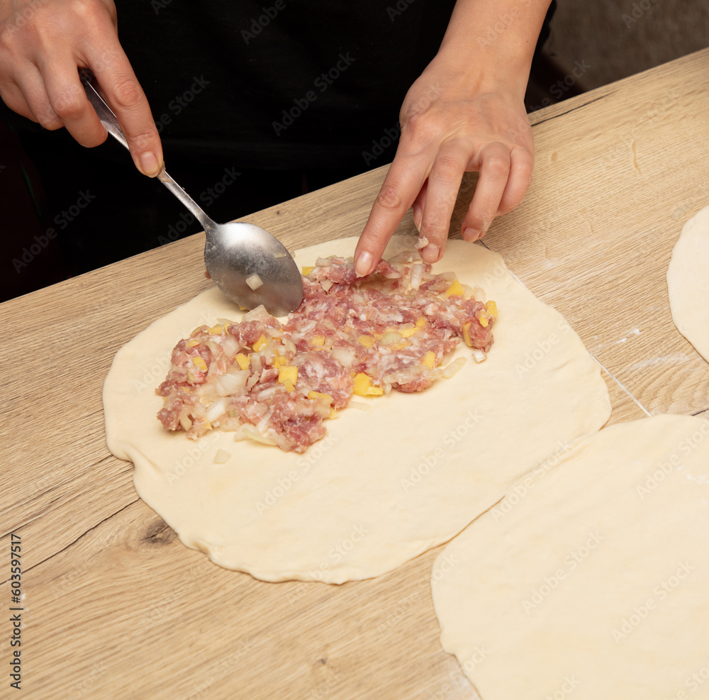 Wall mural Preparing pizza dough with meat, onions and spices on wooden table