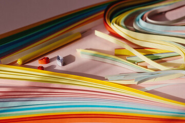 Paper and quilling tools on a pink background with space for text and design.