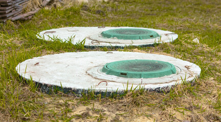 Naklejka premium Green manhole cover on the grass in the park.