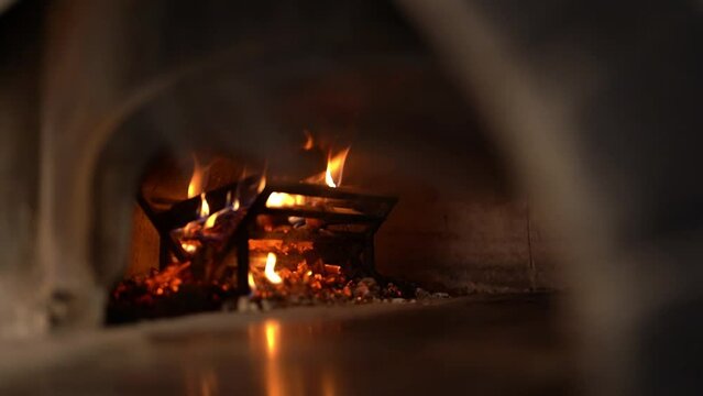 Front view moving image of burning fire flames and firewood in custom made pizza furnace, preparing for baking pizza 