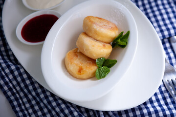 Round cottage cheese pancakes in a white plate on a blue background. Food breakfast. Healthy food.