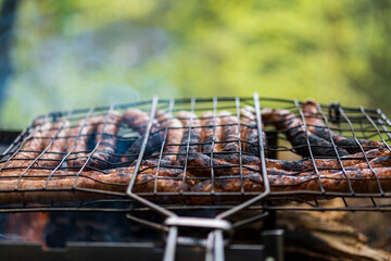 BBQ in the garden. Grilling sausages on barbecue grill.  Bavarian sausages. Barbecue cooking. Cooking food on an open fire.