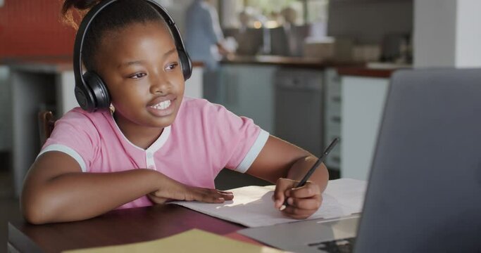 Happy diverse mother with daughter learning with laptop in kitchen in slow motion
