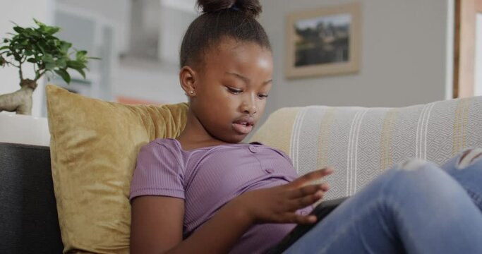 Happy african american girl using smartphone on couch in slow motion