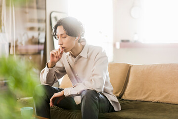 朝、リビングで音楽を聴いている20代の日本人の一人暮らしの男性
