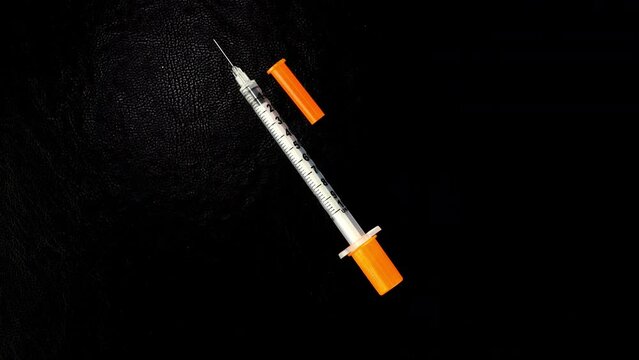 Insulin syringe to manage diabetes inject rotate on black background.