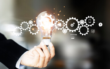 Hand holding light bulb and cog inside. Idea and imagination