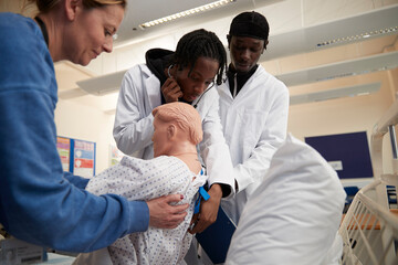Medical students performing medical exam on dummy