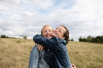 Smiling girl friends hugging in field