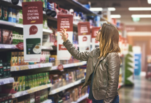 Shopping, woman at grocery store and in aisle searching and decision for product on a shelf. Customer or consumer, shopper for groceries and female person at supermarket or a shop looking for food