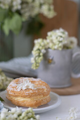 cookies on a plate. A gray cup with the image of a bee, white lilac flowers and a cake. Tea party with flowers